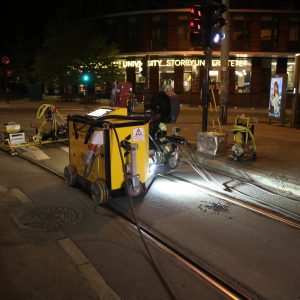 Equipment for fixing embedded tram rail on track at night in Oslo.