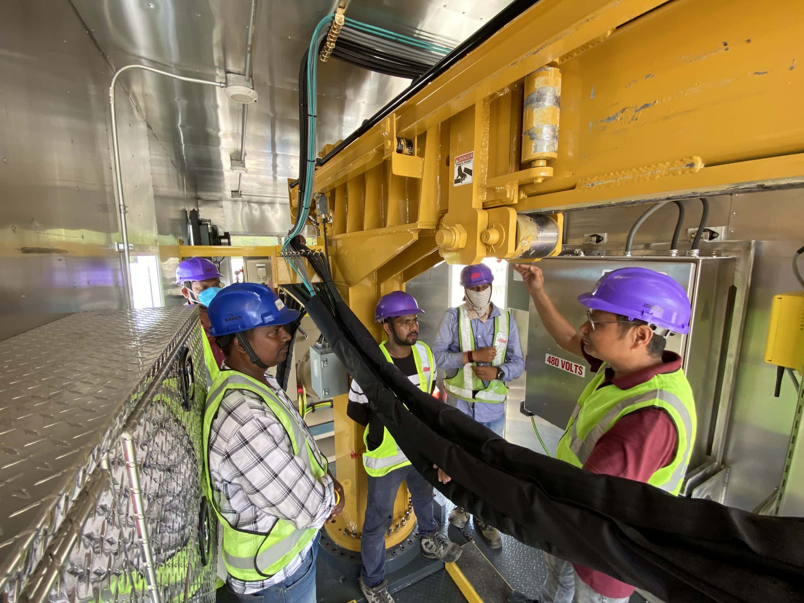 Men inside rail welding container learning about how to operate it.